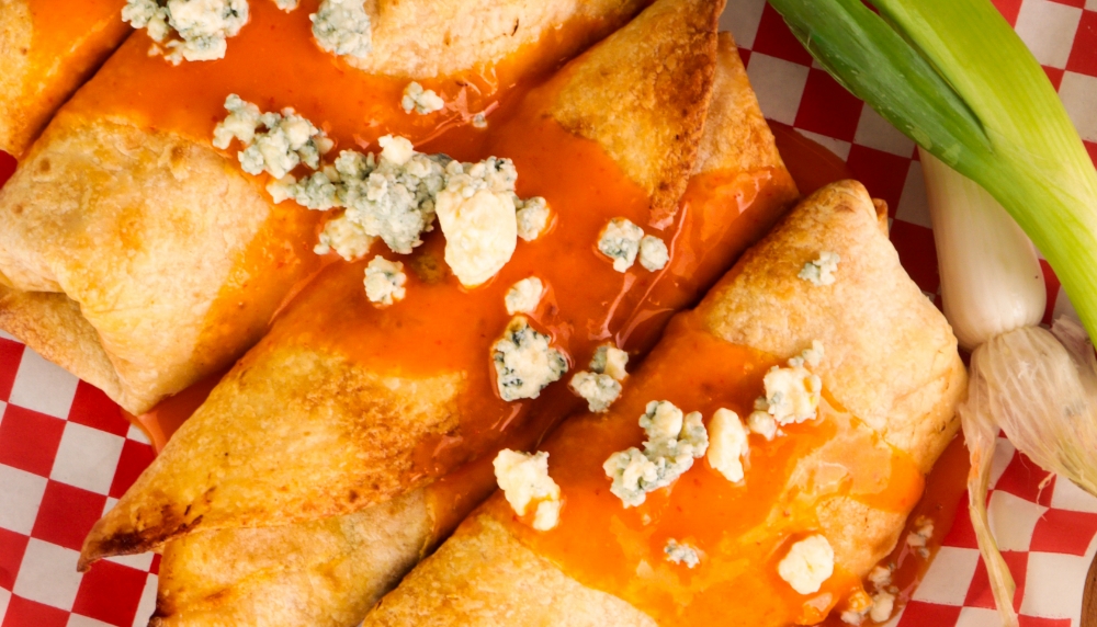 Food rolled into a tortilla, sealed on both ends, baked and covered with buffalo sauce with blue cheese